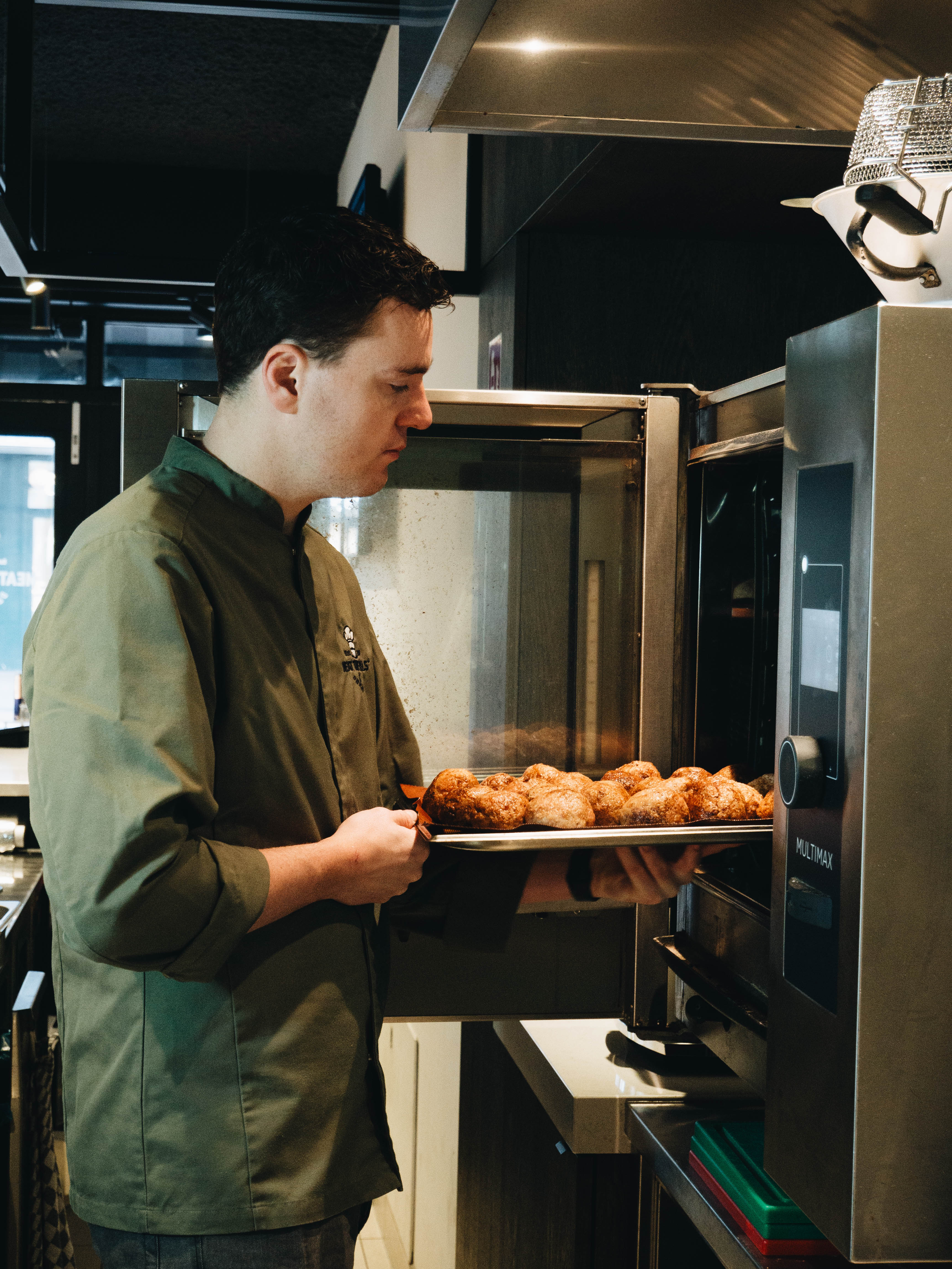 Kok haalt vers gebakken gehaktballen uit de oven in onze open keuken aan de Kinkerstraat